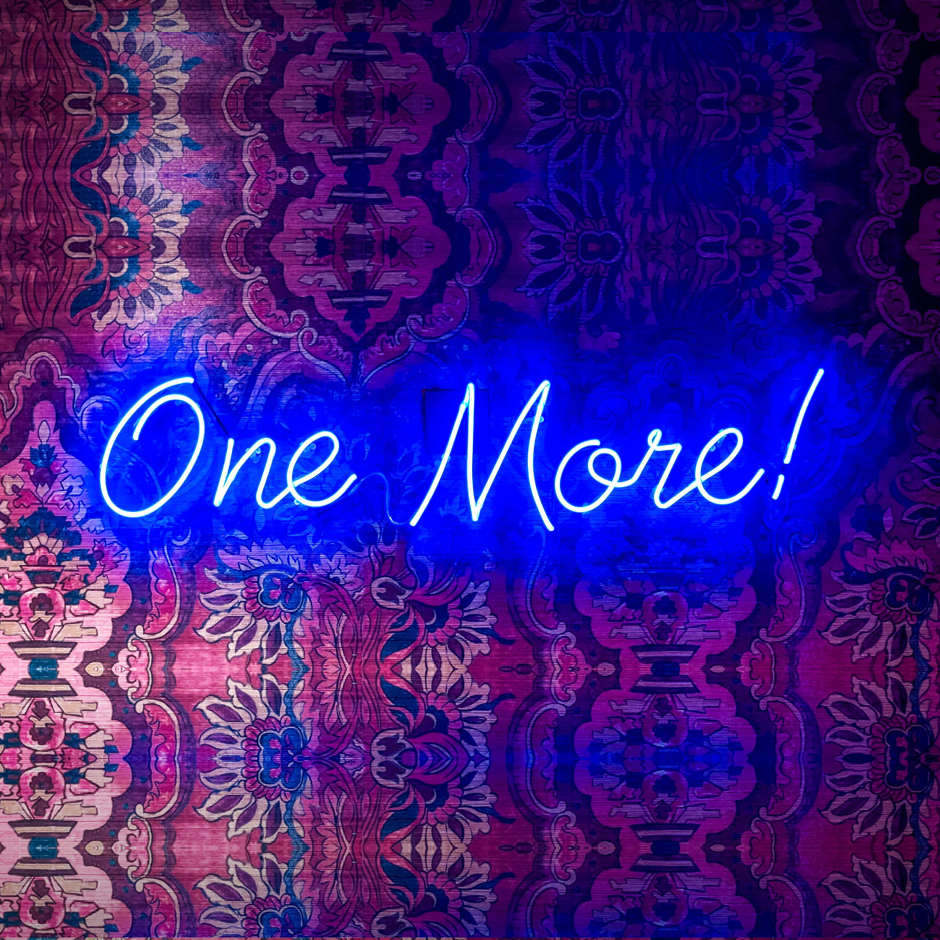 Neon "One More!" sign on patterned fabric