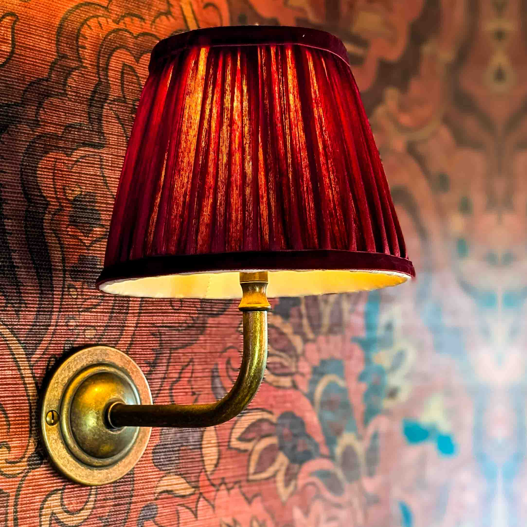 Wall light with pleated red silk shade